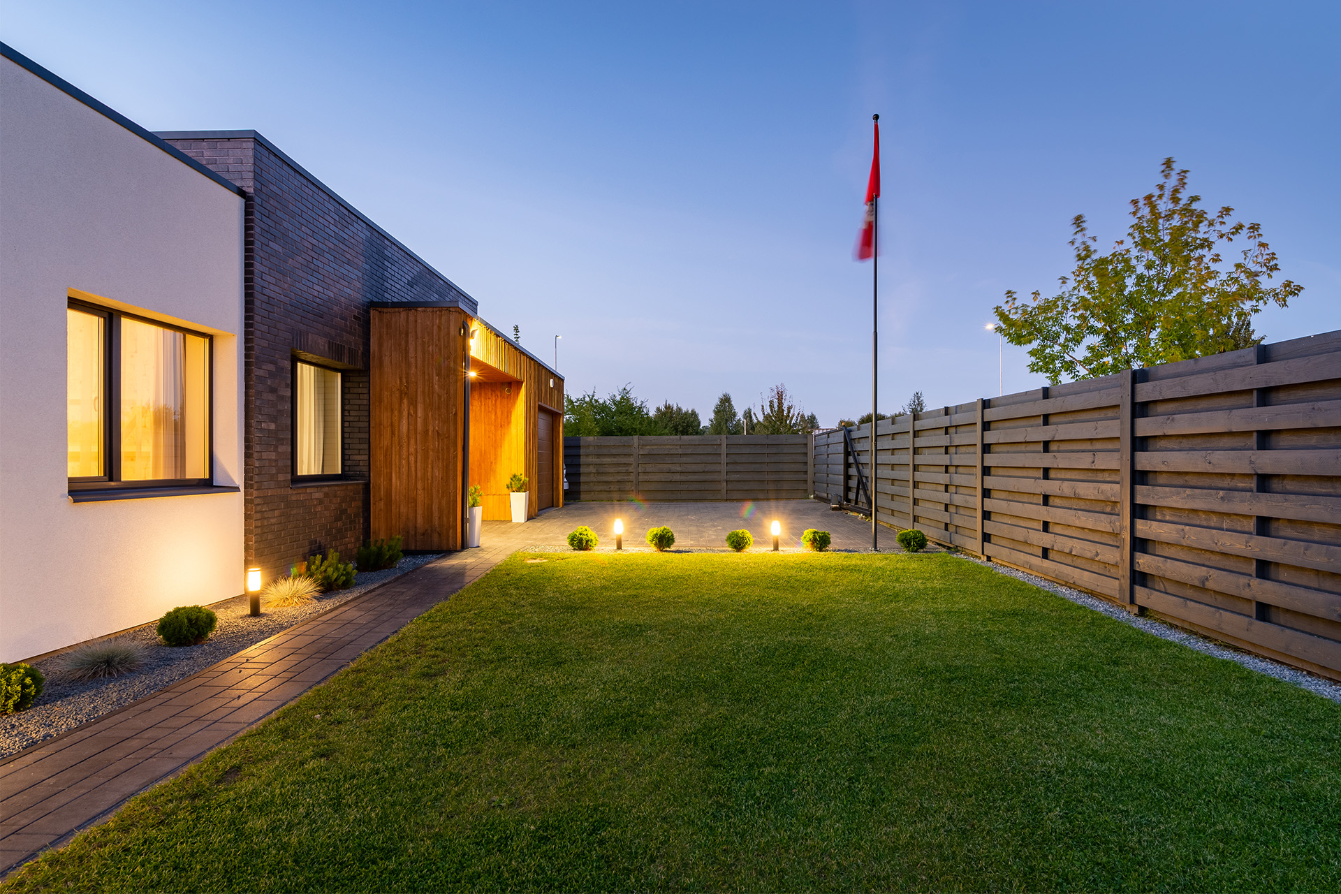 Holzzaun, Kunststoffzaun oder Sichtschutzelemente für den Garten Zaun und Gartentor aus Holz vor einem modernen Einfamilienhaus
